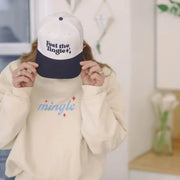 girl wearing a brand-new 'Feel the Tingle' trucker hat with a navy brim and white front, paired with a beige sweatshirt