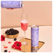 Mingle non-alcoholic blackberry bellini in a champagne flute, accompanied by fresh blackberries and hibiscus flowers.